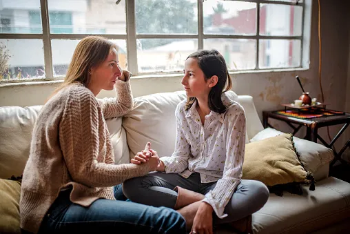 two seated women holding hands